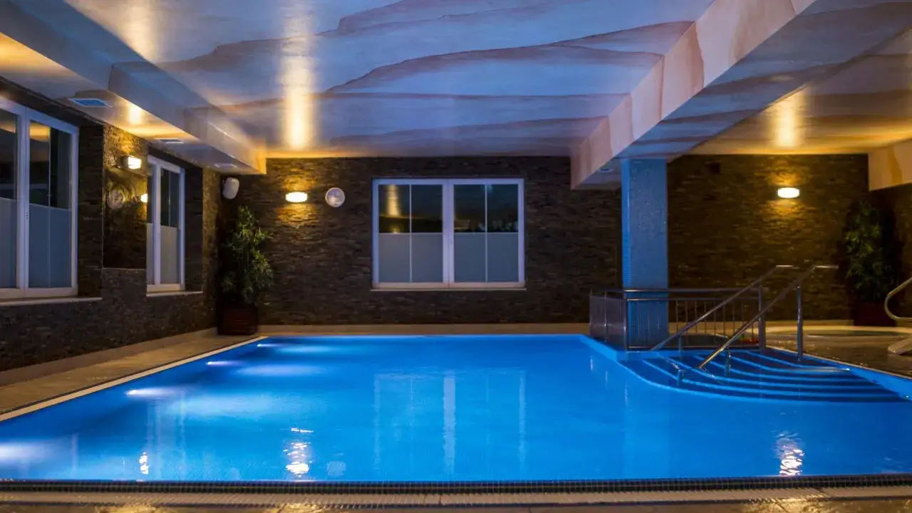 Basen w hotelu Skalite Spa & Wellness w Szczyrku. Błękitna woda, kamienne ściany i nastrojowe oświetlenie tworzą relaksującą atmosferę.