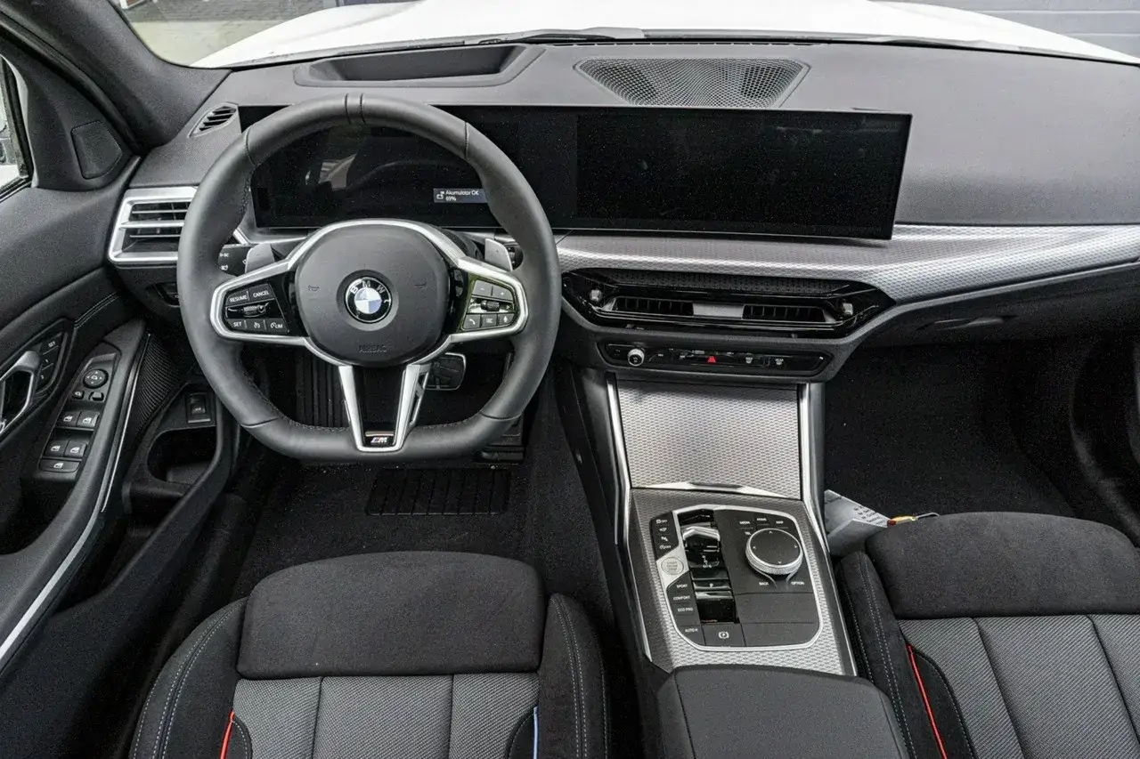 Wnętrze BMW 330i G20: kierownica, duży ekran multimedialny, konsola środkowa z selektorem biegów i sportowe fotele.