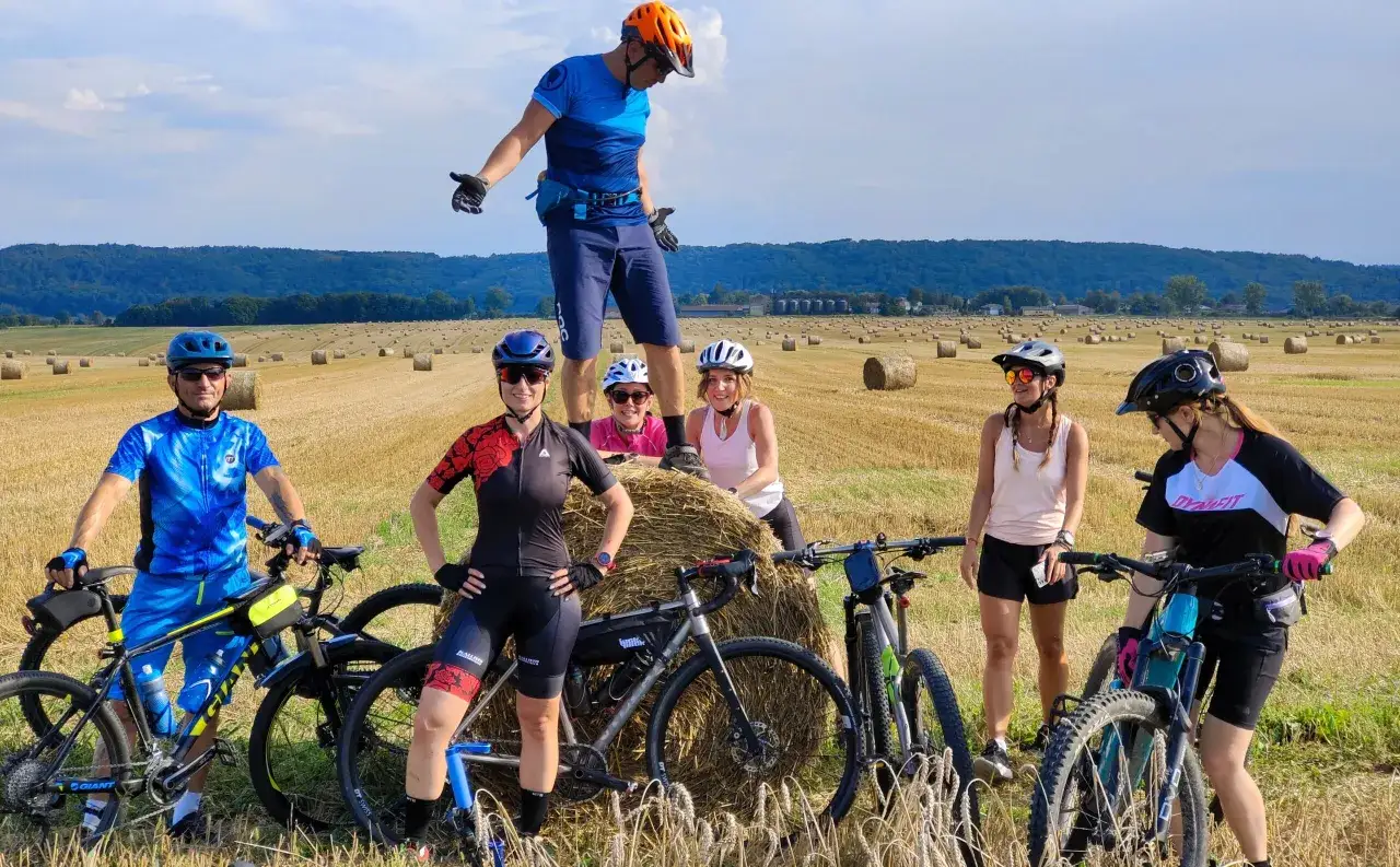 Grupa rowerzystów na tle pól ze słomą, gotowa do podboju trasy rowerowej Szlak Orlich Gniazd.