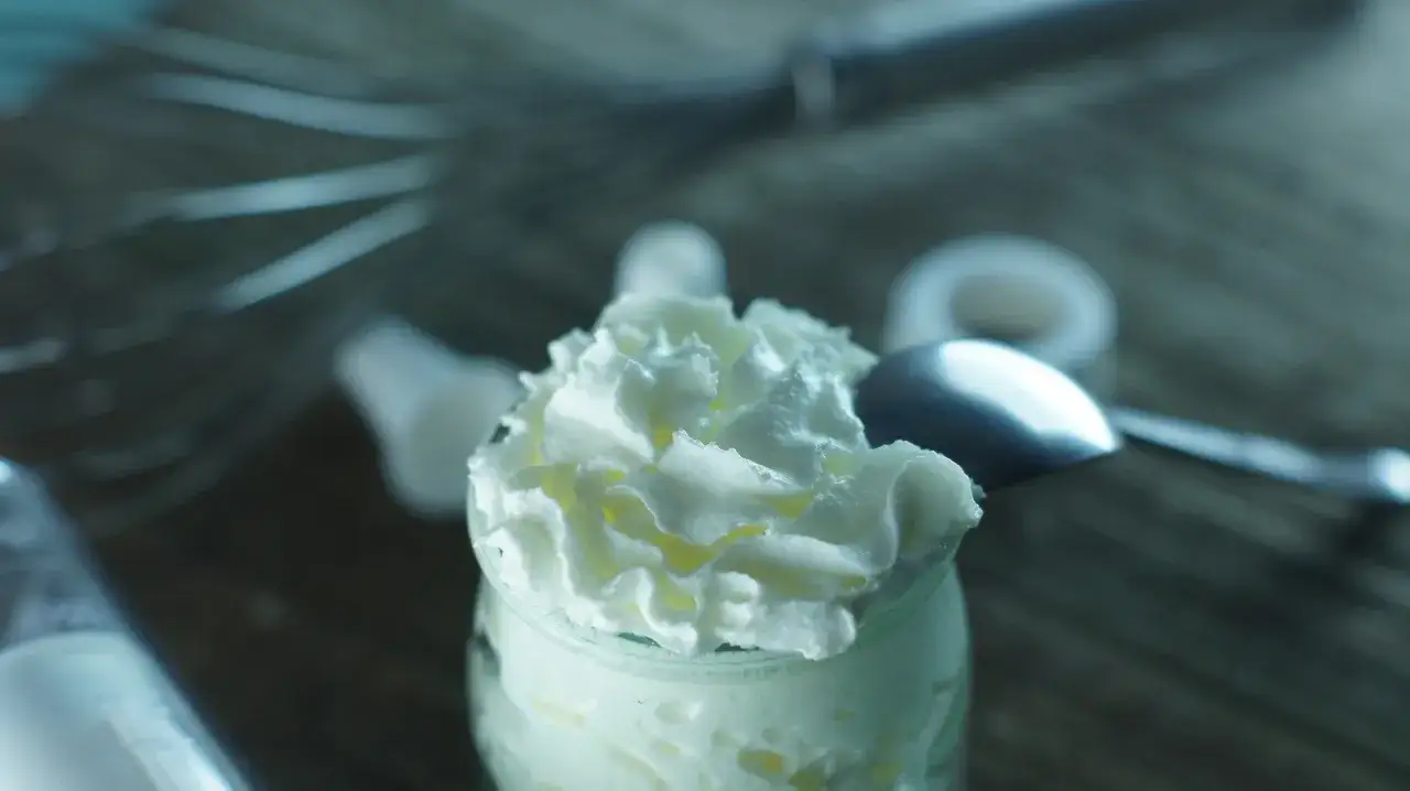 Postre cremoso en vaso, ideal para sustituir nata para cocinar por leche. Una cuchara reposa sobre la espuma.