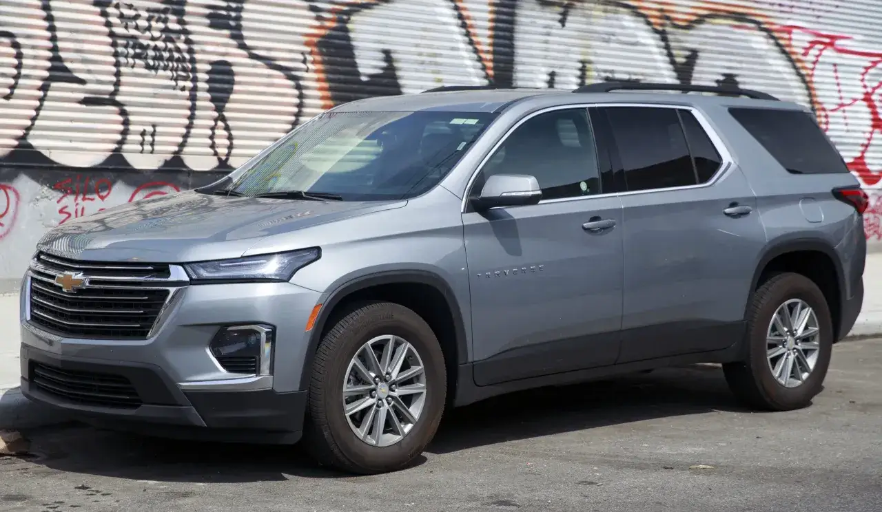 Srebrny Chevrolet Traverse, jeden z wielu popularnych chevrolet modele, zaparkowany na tle graffiti.