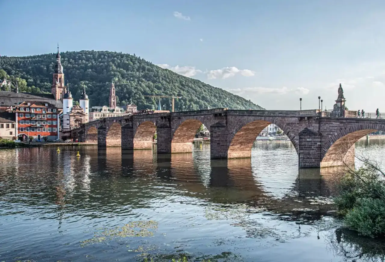 Heidelberg's Alte Br&uuml;cke, ein klassischer Fotospot, spiegelt sich im Neckar. Im Hintergrund die Altstadt und der K&ouml;nigstuhl.
