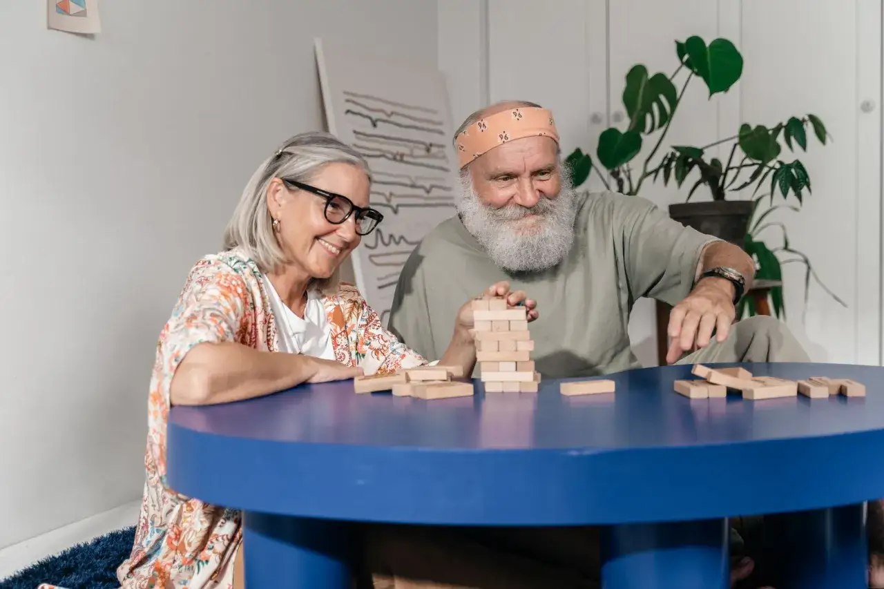 Uśmiechnięta para seniorów gra w Jengę. To świetne gry dla par, które budują napięcie i śmiech.