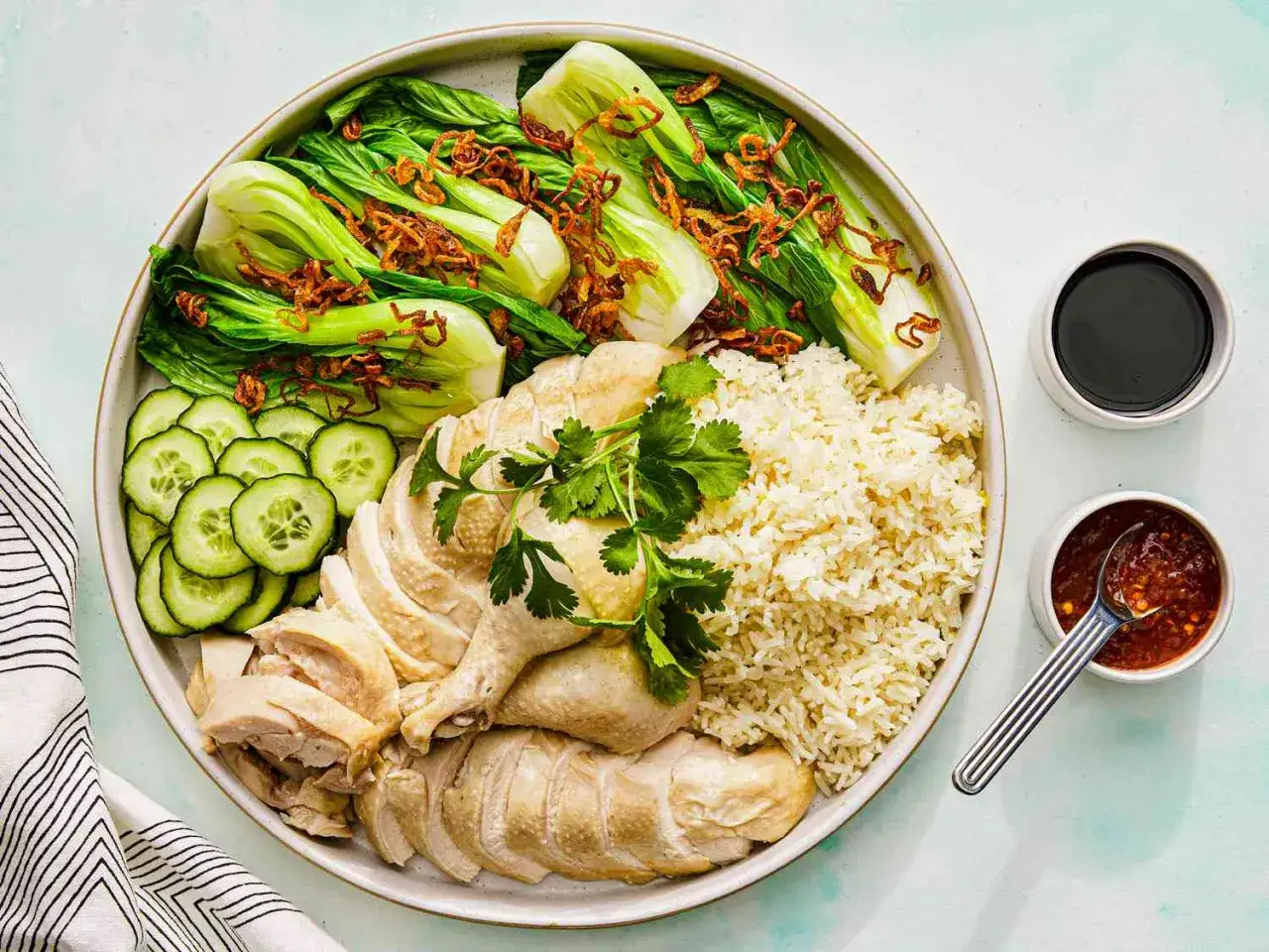 Pyszny kurczak hanoi z ryżem, pak choi, ogórkiem i sosami. Idealny posiłek dla miłośników azjatyckich smaków.