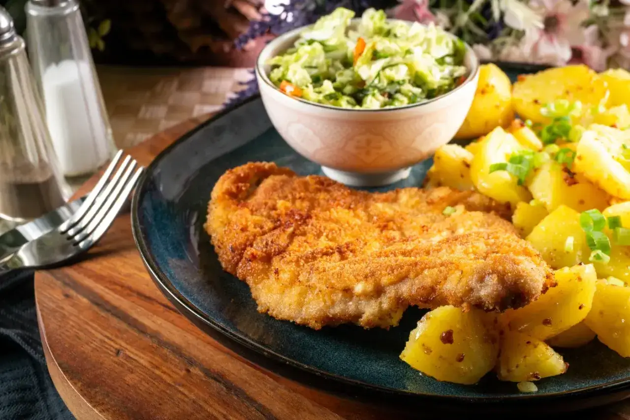 Złocisty kotlet słoneczny, chrupiący i apetyczny, podany z ziemniakami i świeżą surówką. Idealny posiłek na słoneczny dzień.
