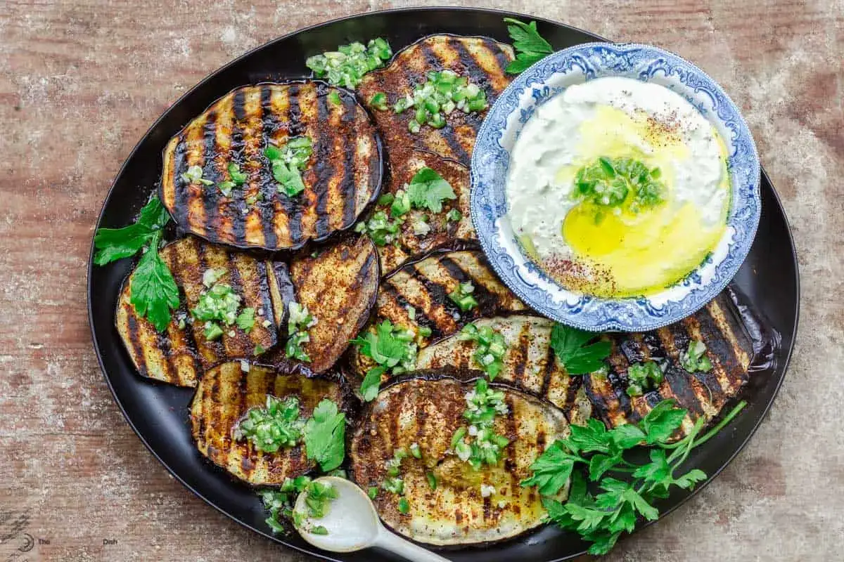 Gegrillte Auberginenscheiben mit Kr&auml;utern und einem Dip. Perfekt, um Aubergine zuzubereiten und zu genie&szlig;en.