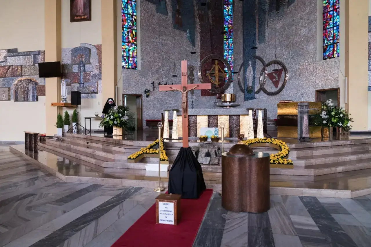 Wielka Sobota w kościele. Siostra zakonna przy ołtarzu, krzyż i ozdoby wielkanocne.