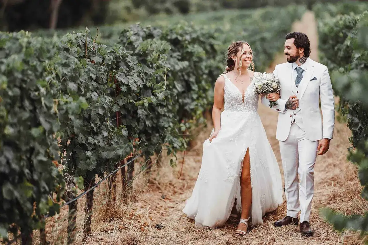 Un couple de jeunes mariés se promène main dans la main dans un vignoble, un beau moment capturé pour leurs photos mariage.