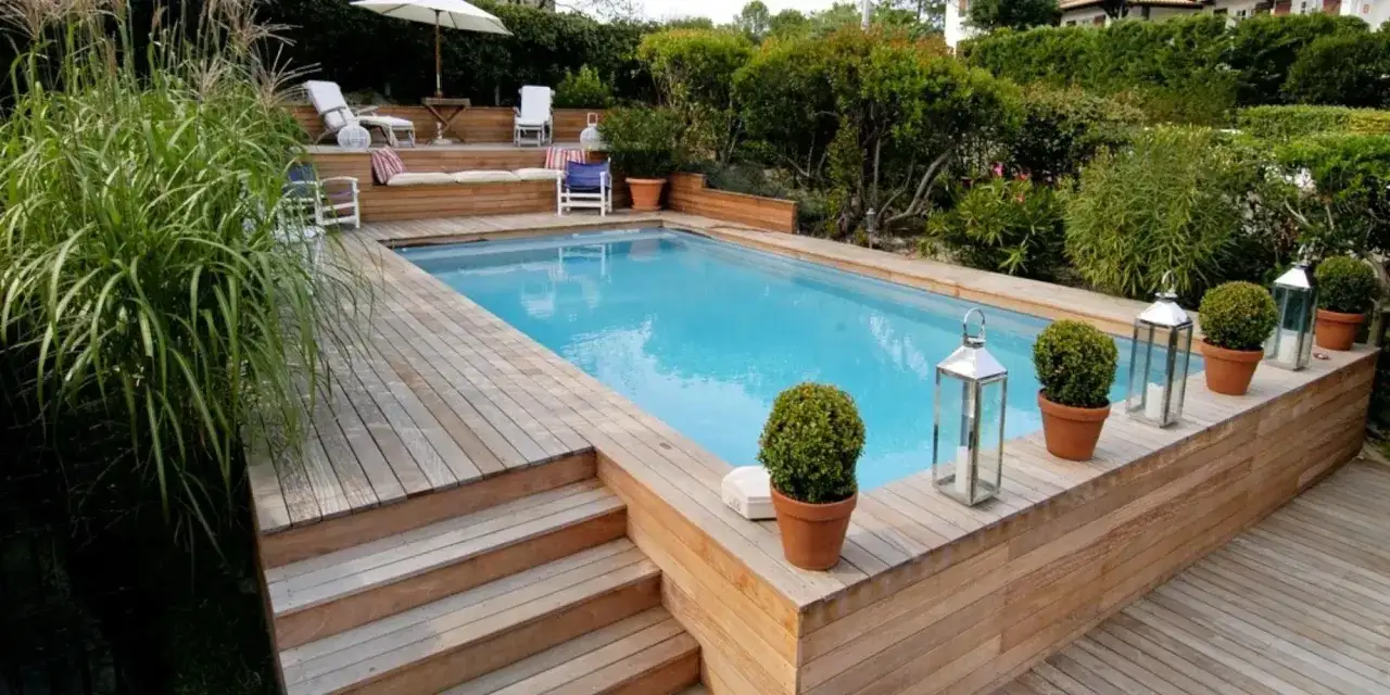 Magnifique **habillage piscine semi enterrée** en bois, avec terrasse, escaliers et végétation luxuriante.