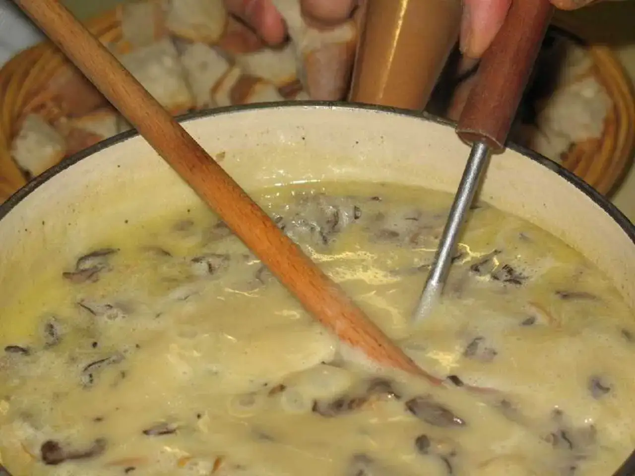 Une d&eacute;licieuse fondue savoyarde aux c&egrave;pes mijote dans un caquelon, pr&ecirc;te &agrave; &ecirc;tre d&eacute;gust&eacute;e avec du pain.