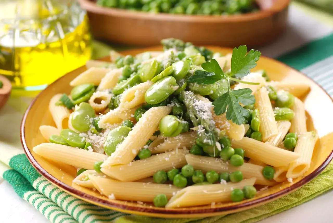 Penne z bobem i groszkiem, posypane parmezanem. Idealne danie, by pokazać, z czym jeść bób.