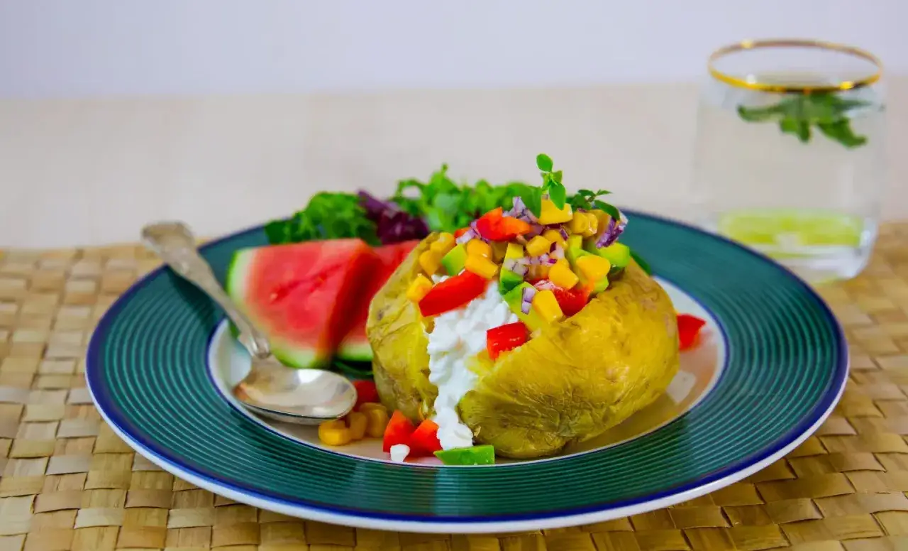 En saftig bakad potatis med en f&auml;rgglad fyllning av majs, paprika, l&ouml;k och avokado. Serveras med vattenmelon och en frisk sallad.