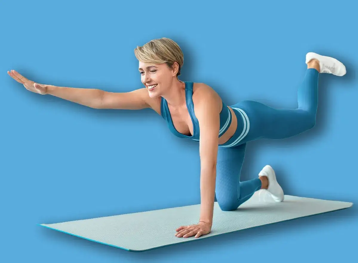 Frau in Sportkleidung macht eine Übung auf einer Matte. Sie trainiert ihren Körper, um fit zu bleiben, vielleicht um **2 mal am Tag trainieren** zu können.