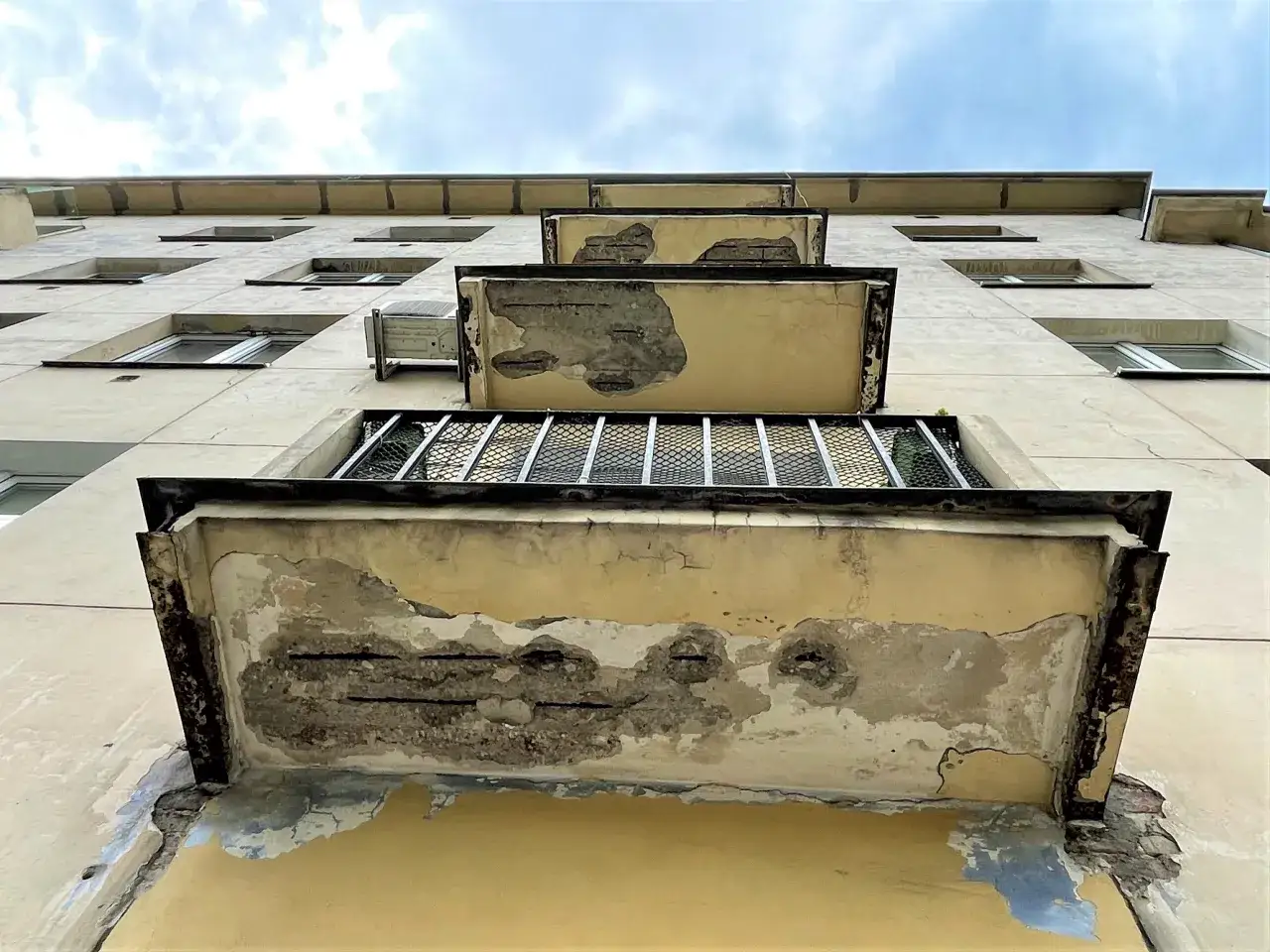 Zniszczone balkony bloku mieszkalnego, z widoczną korozją zbrojenia. Potrzebny jest specjalny inhibitor, by zatrzymać postęp degradacji.