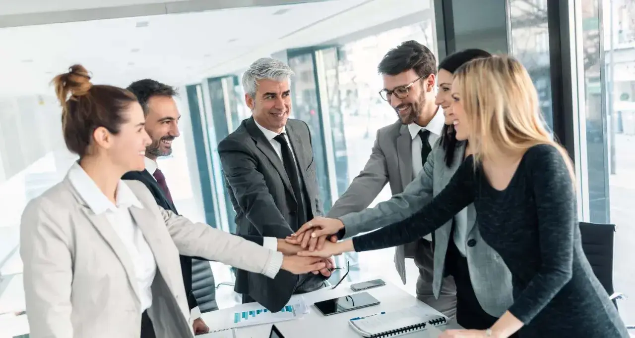Equipo unido, manos entrelazadas, un ejemplo de c&oacute;mo mejorar la comunicaci&oacute;n interna de una empresa.