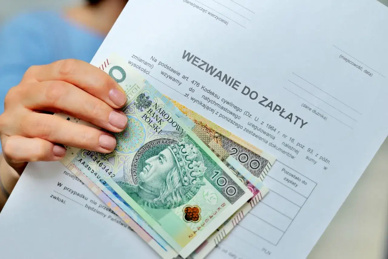 Dłoń trzyma wezwanie do zapłaty i polskie banknoty. Dokument dotyczy uregulowania należności, a jego treść sugeruje możliwość przedawnienia długu.