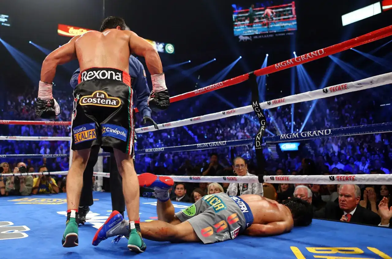 A boxer lies on the canvas after a knockout during the Pacquiao vs Marquez fight. His opponent stands over him, victorious.