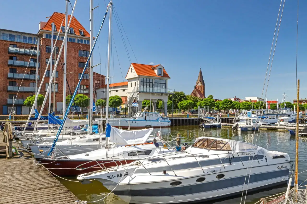 Segelboote und Yachten im Hafen von Barth an der Ostsee. Im Hintergrund rote Backsteingebäude und eine Kirche.