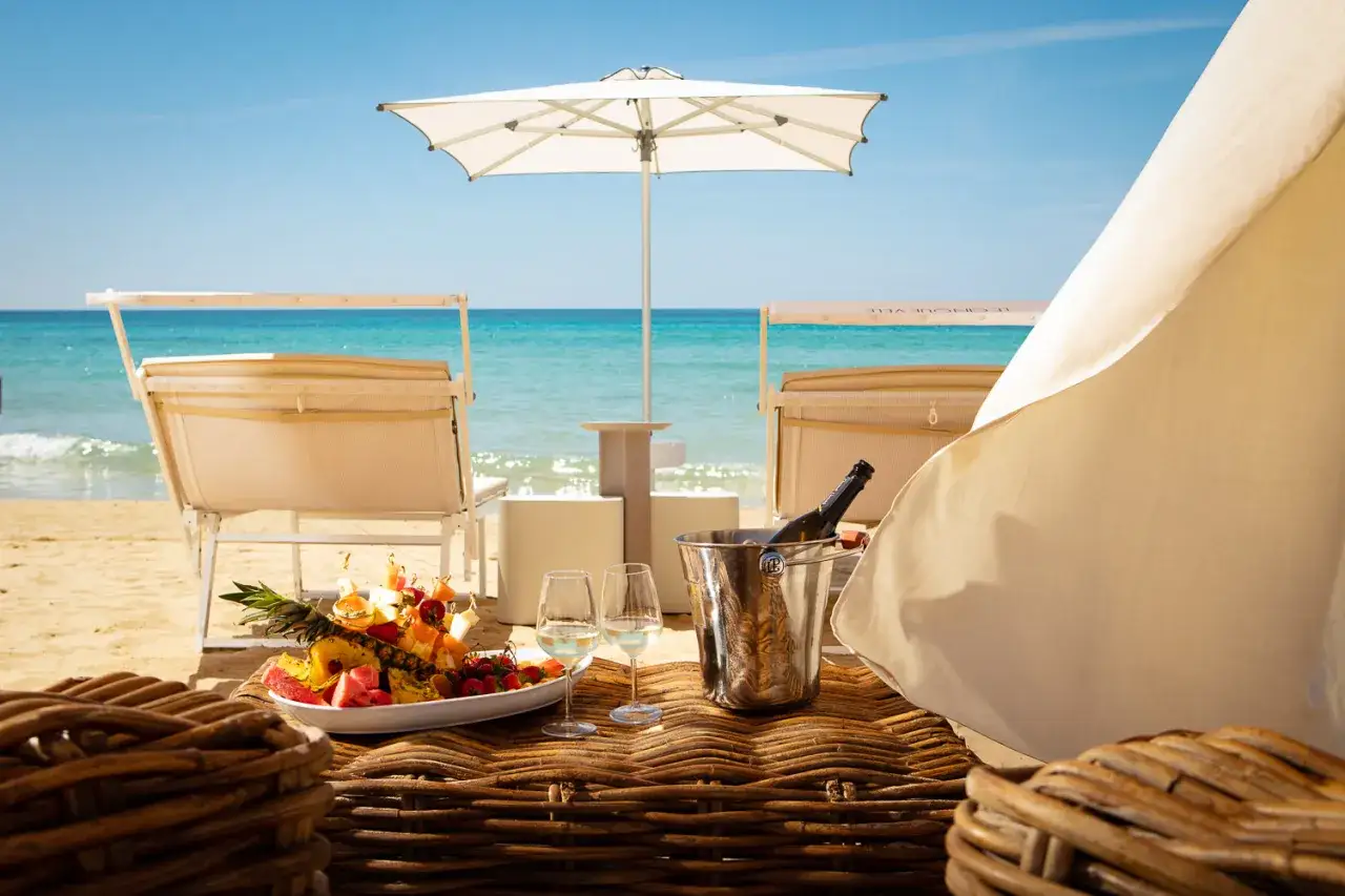 Relax sui lettini, con frutta fresca e champagne, in uno dei migliori beach club della Puglia.