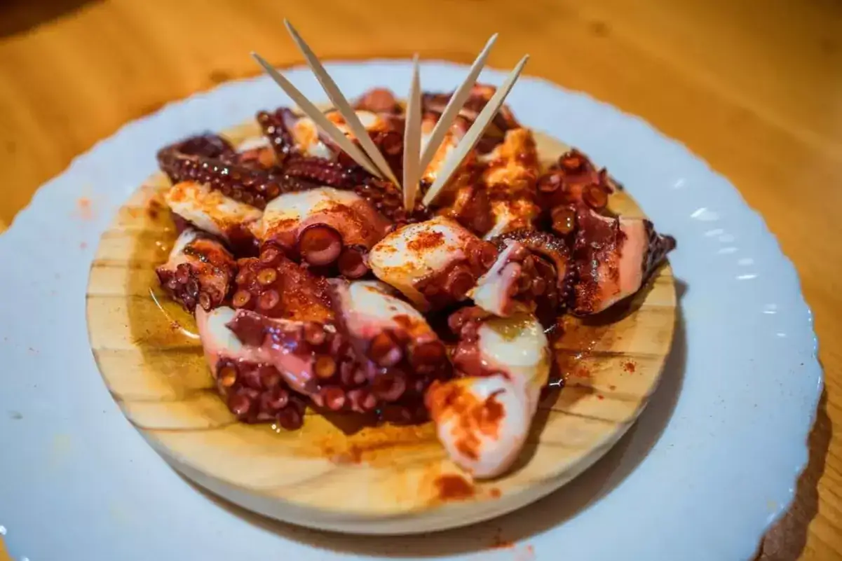 Pulpo a la gallega, un plato que representa los países con mejor gastronomía. Tentáculos tiernos con pimentón, servidos en madera.