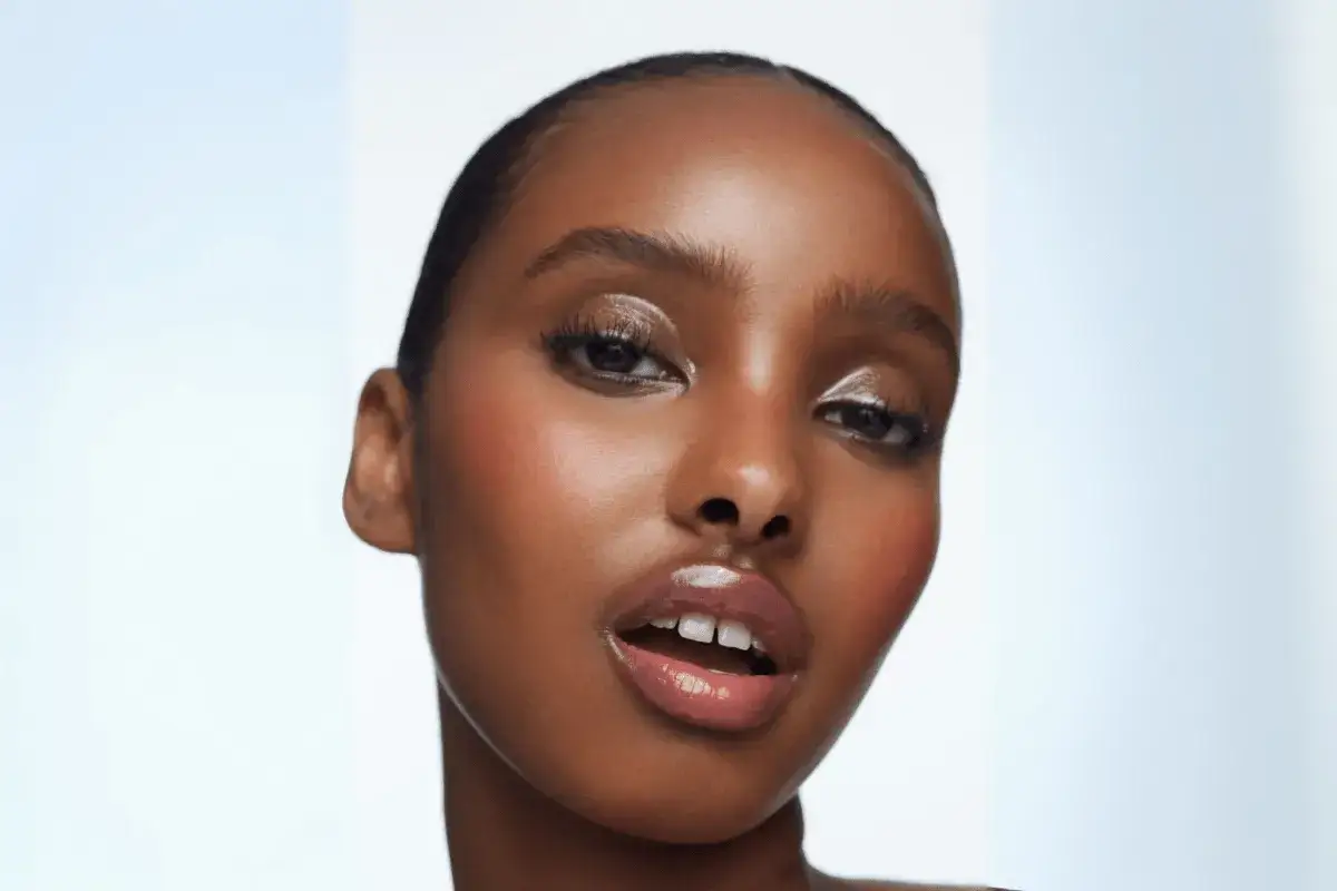 Rostro de mujer con un maquillaje aesthetic que resalta sus ojos con brillo y labios jugosos.