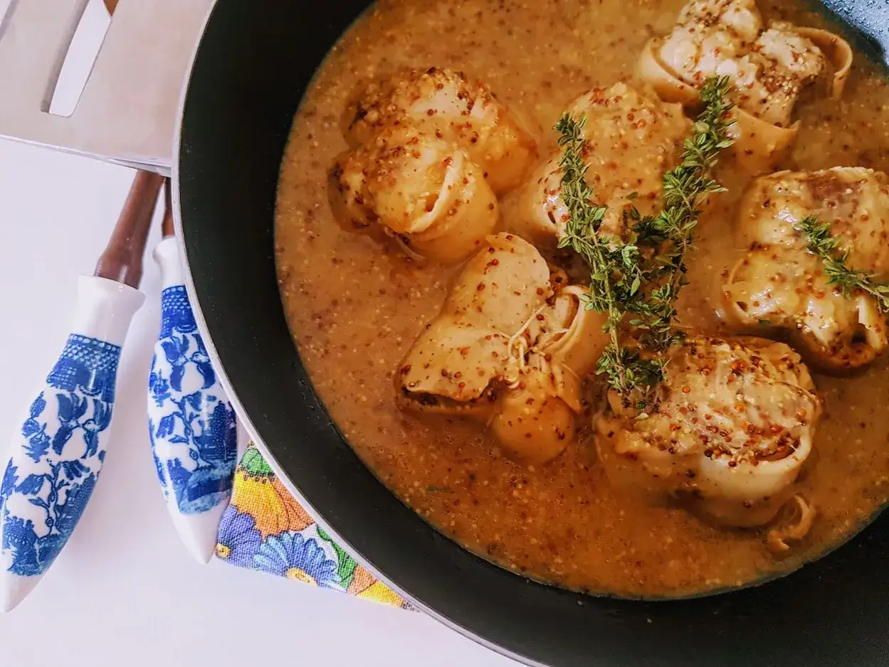 Cuisson paupiette de veau dans une sauce moutard&eacute;e, garnie de thym frais. Des ustensiles d&eacute;cor&eacute;s sont &agrave; c&ocirc;t&eacute;.