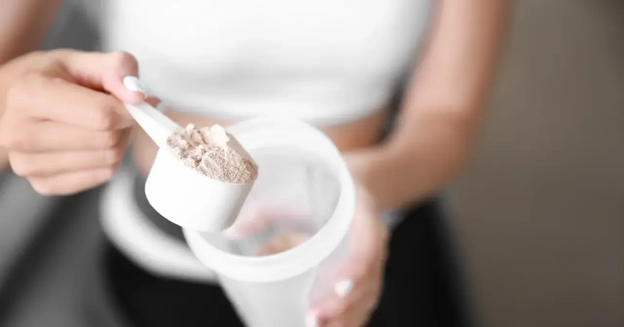 Kobieta dodaje proszek do shakera. Czy shake proteinowy jest zdrowy? To pytanie zadaje sobie wiele os&oacute;b dbających o formę.