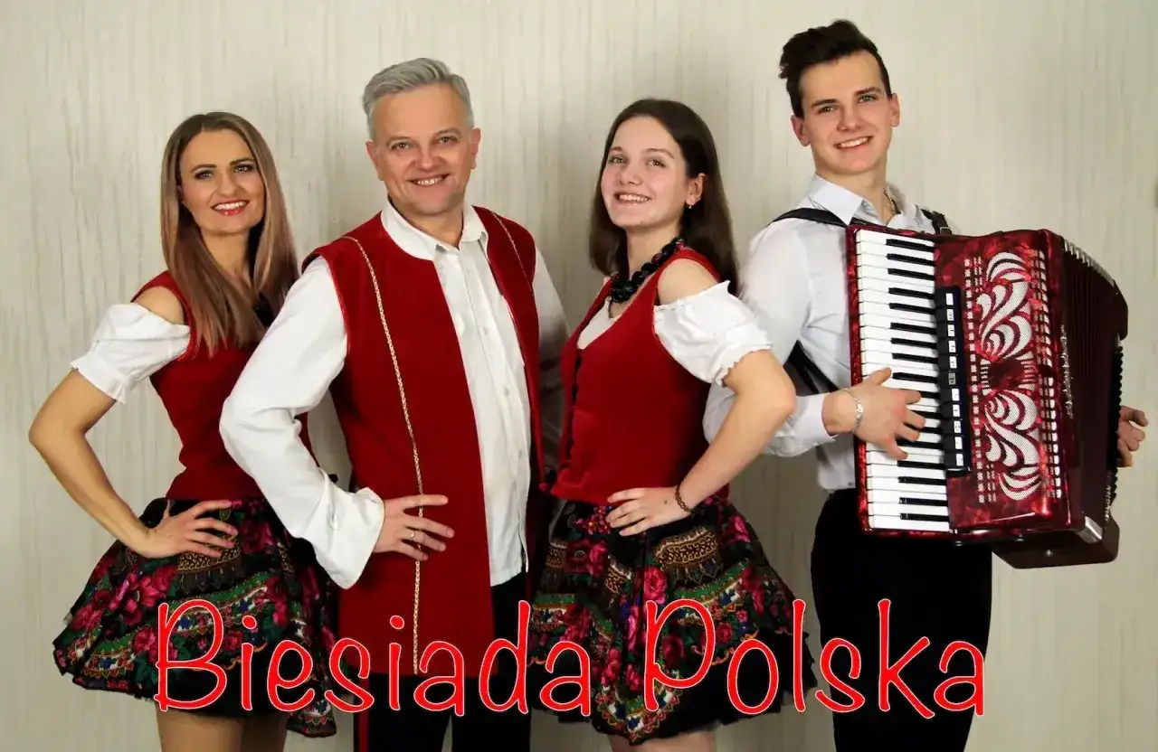 Zespół grający muzykę biesiadną. Młody mężczyzna gra na akordeonie, obok niego stoją trzy osoby w strojach ludowych.