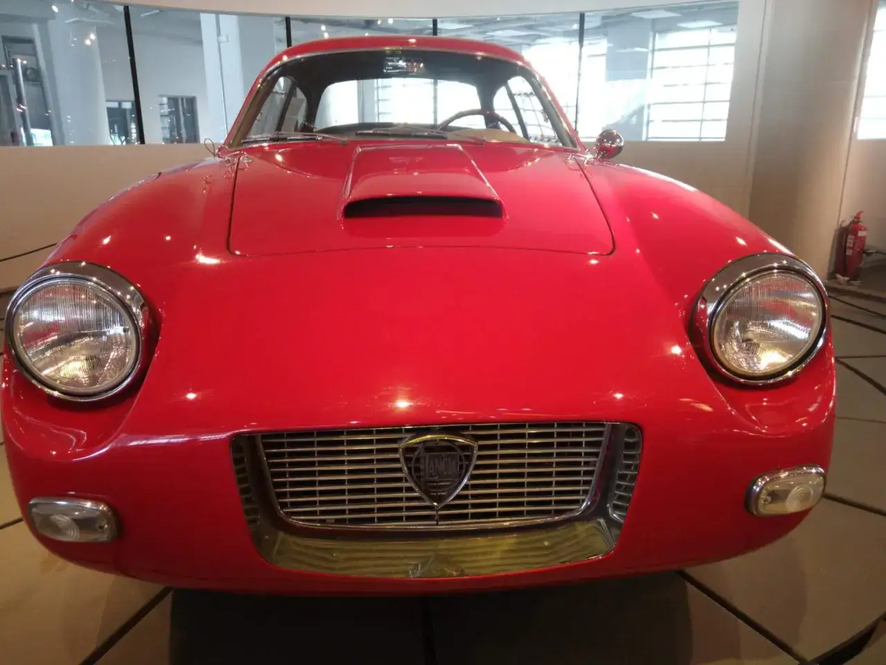 Ein leuchtend roter italienischer Oldtimer mit markantem Kühlergrill und Lancia-Logo.