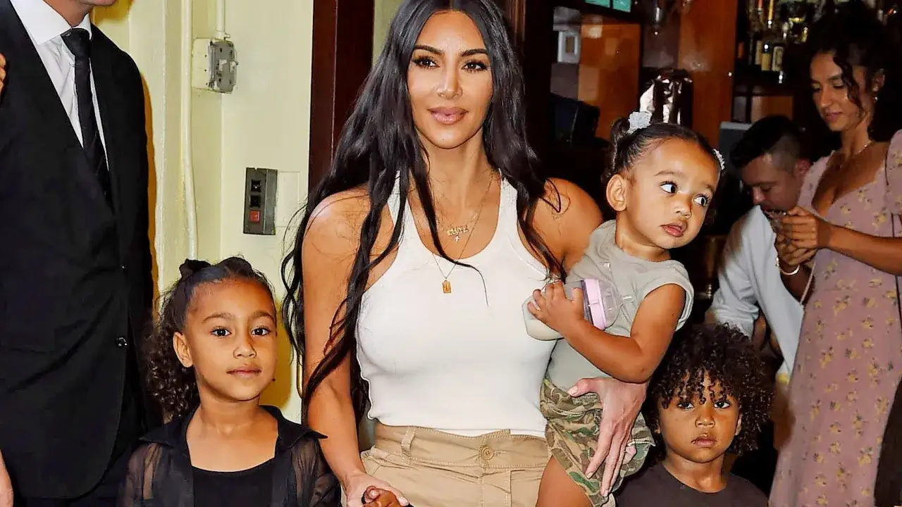 Kim Kardashian med sina kim kardashian barn. En flicka med svart kl&auml;nning, en pojke med brun tr&ouml;ja och en bebis i famnen.
