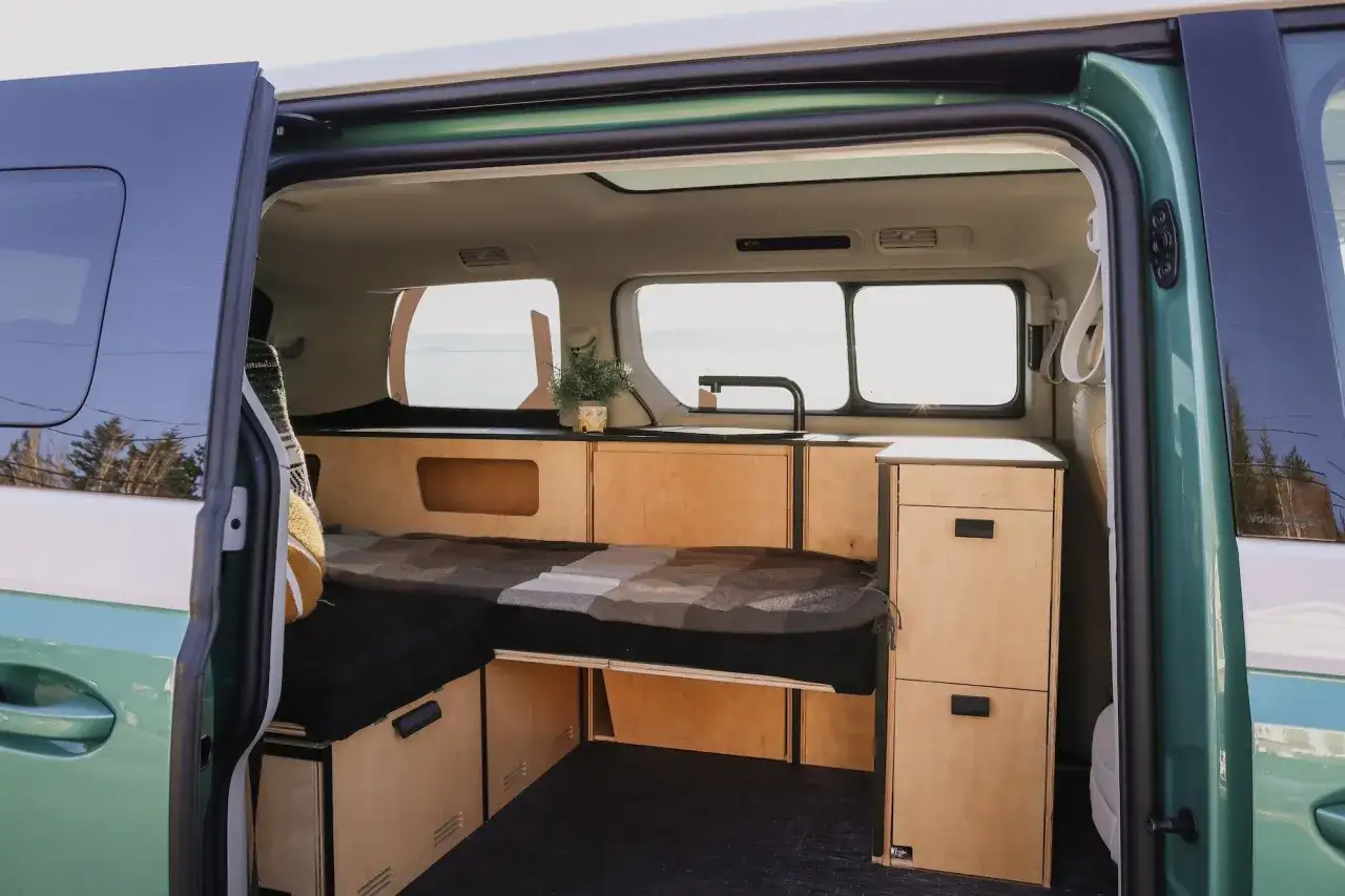Interi&ouml;r i en gr&ouml;n id buzz camper van med s&auml;ng, k&ouml;k och f&ouml;rvaring i tr&auml;. Perfekt f&ouml;r &auml;ventyr!