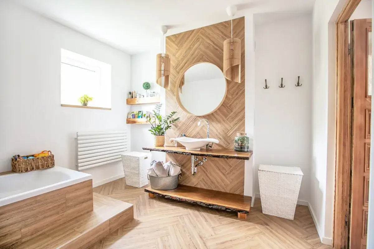 Jasna łazienka z wanną, umywalką i drewnianymi elementami. Małe okno łazienkowe wymiary idealnie pasują do minimalistycznego stylu.