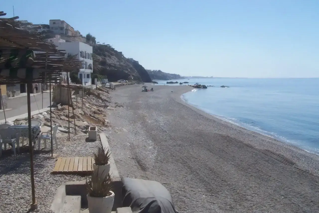 Playa de guainos almer&iacute;a, con casas blancas en la ladera y el mar azul.