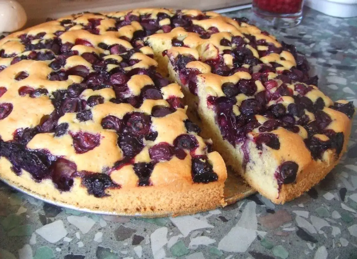 Pyszne ciasto ucierane z bor&oacute;wkami na dużą blachę, z kawałkiem odciętym dla spr&oacute;bowania.