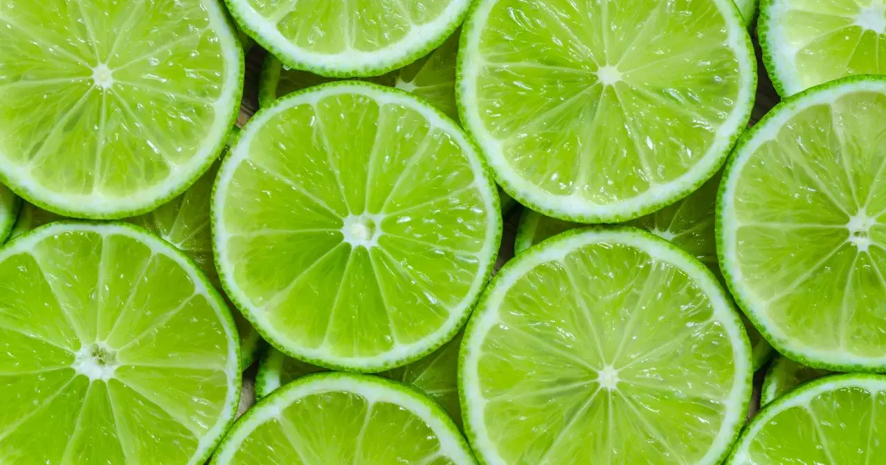 Plasterki soczystych, zielonych limonek tworzą orzeźwiający wzór. Sok z limonki właściwości odżywcze i orzeźwiający smak.