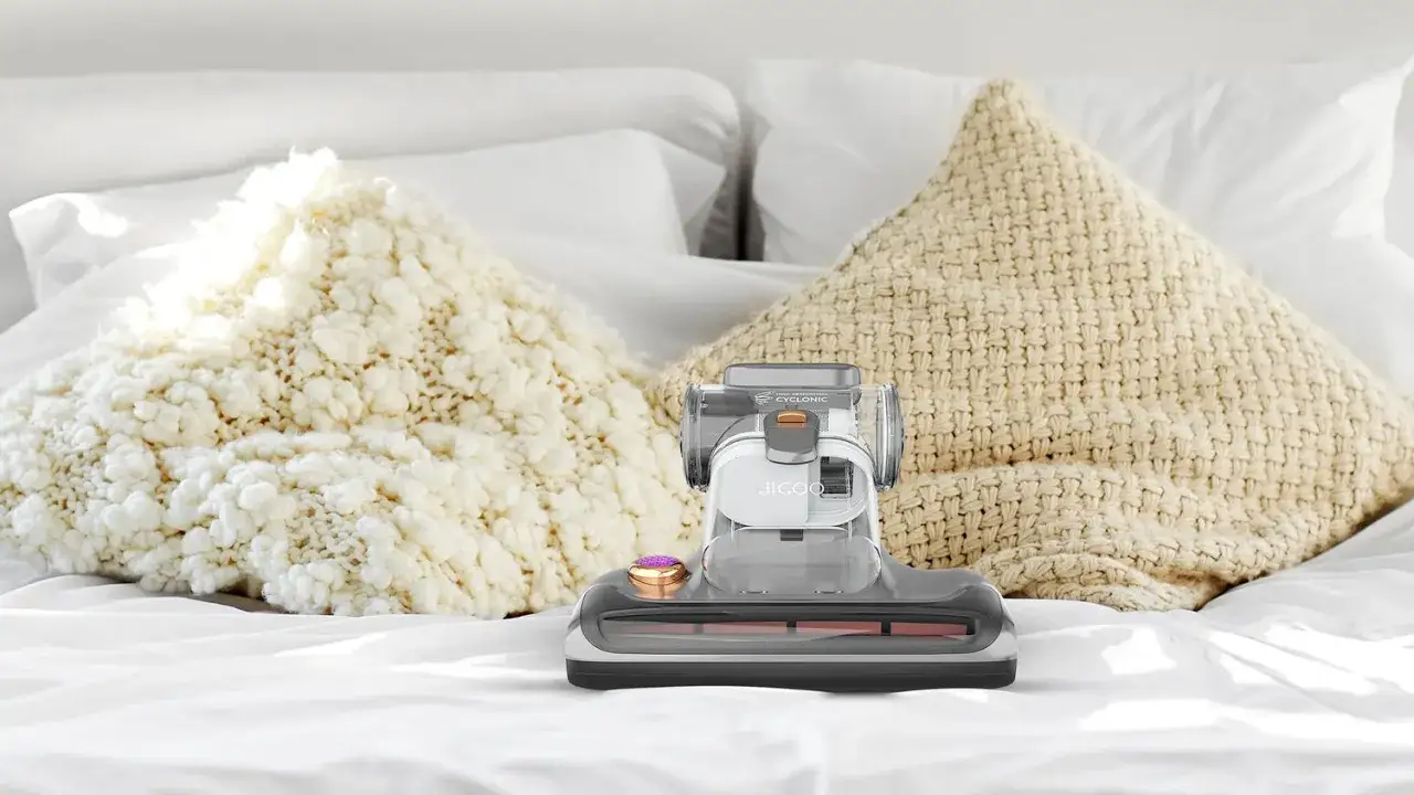 A handheld vacuum cleaner sits on a bed with pillows, ready to tackle how to get dust mites out of pillows for a cleaner sleep.
