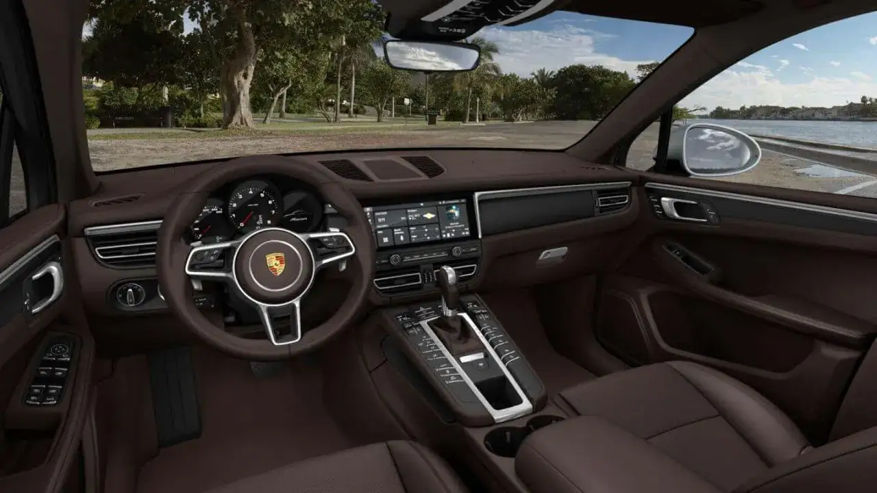 Wnętrze Porsche Macan. Eleganckie, brązowe skóry, nowoczesny kokpit i ekran multimedialny. Idealny na wakacje, a porsche macan cena jest w zasięgu ręki.