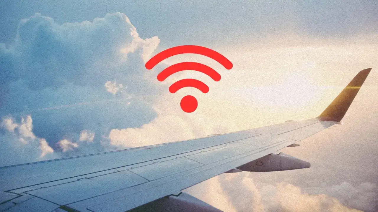 Widok z okna samolotu na chmury i skrzydło. Czerwony symbol Wi-Fi sugeruje, czy w samolocie jest wifi.