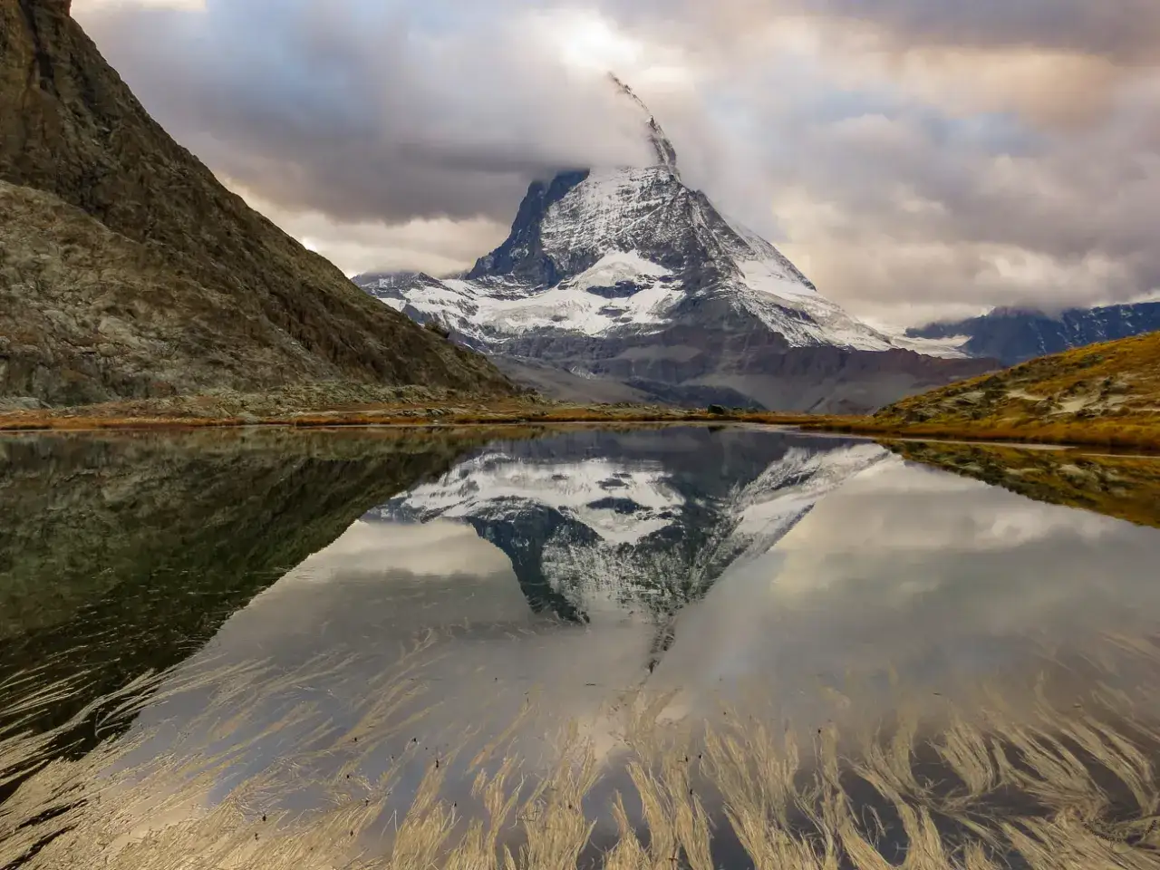 Majestatyczny szczyt Matterhorn odbija się w spokojnym jeziorze. Idealne miejsce na szwajcarskie wakacje.