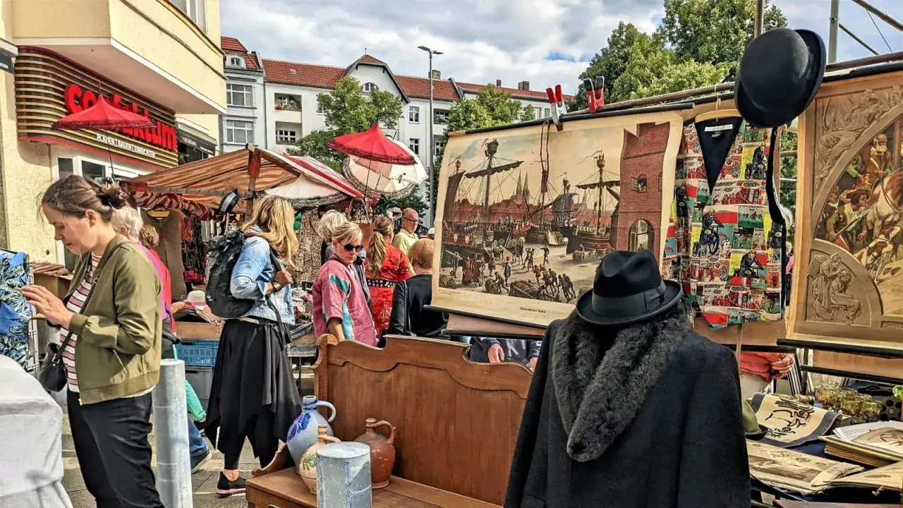 Buntes Treiben auf einem antik flohmarkt. Menschen st&ouml;bern zwischen Gem&auml;lden, Kleidung und alten Gegenst&auml;nden.
