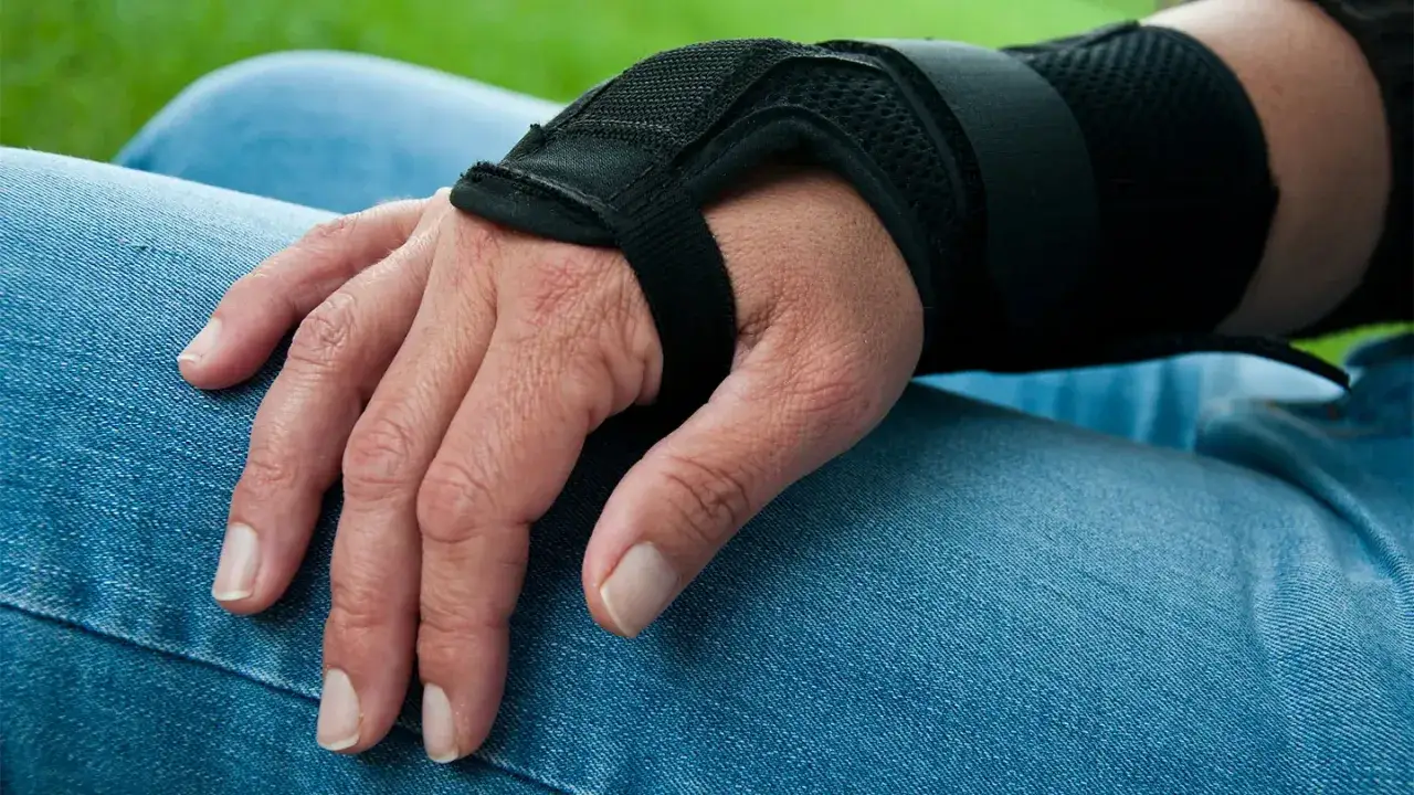 Dłoń w stabilizatorze, po ciężkiej pracy fizycznej. RZS utrudnia codzienne czynności, ale rehabilitacja pomaga.