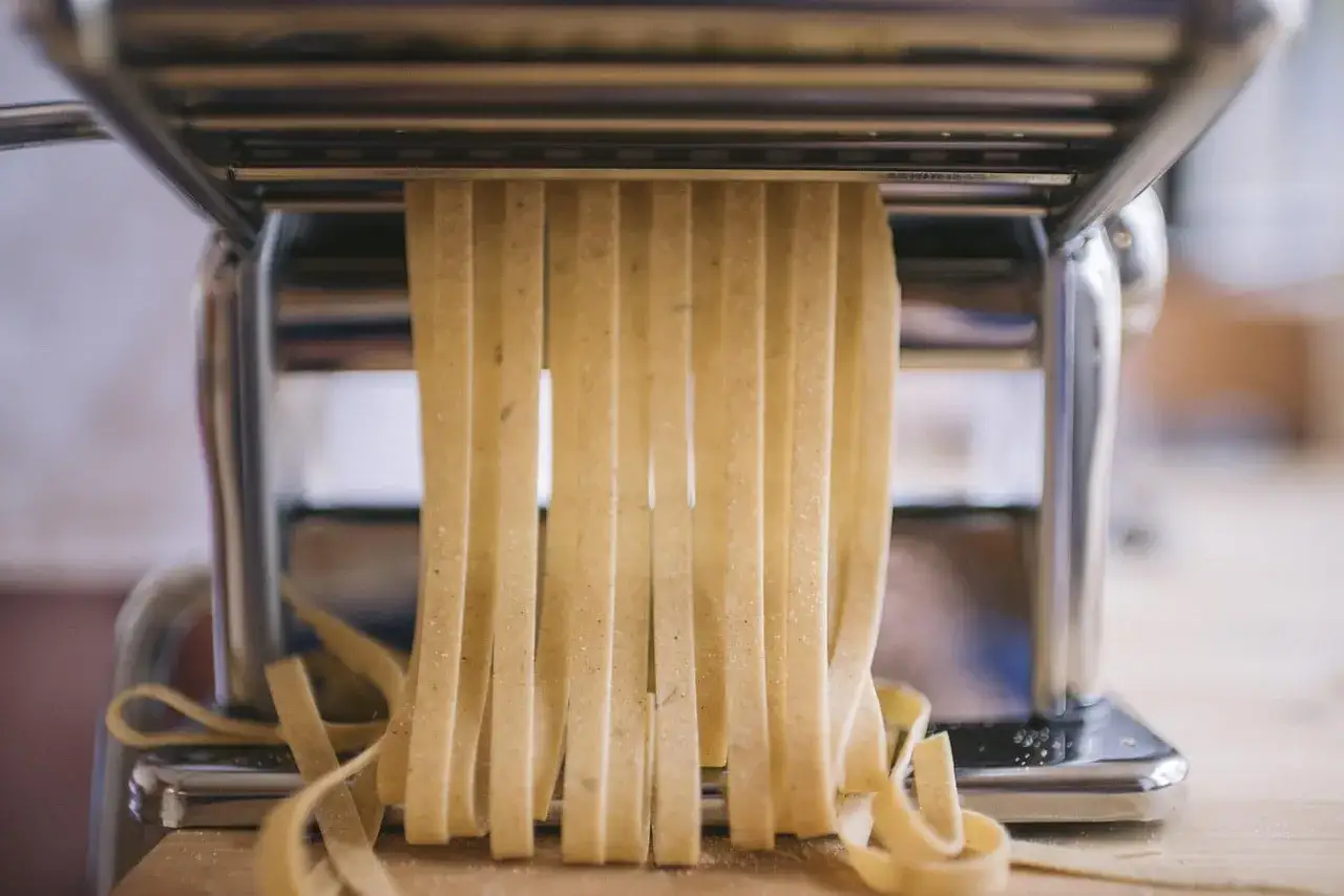 La machine à pâtes coupe des tagliatelles fraîches, parfaites pour une recette pâte fraîche chef italien.