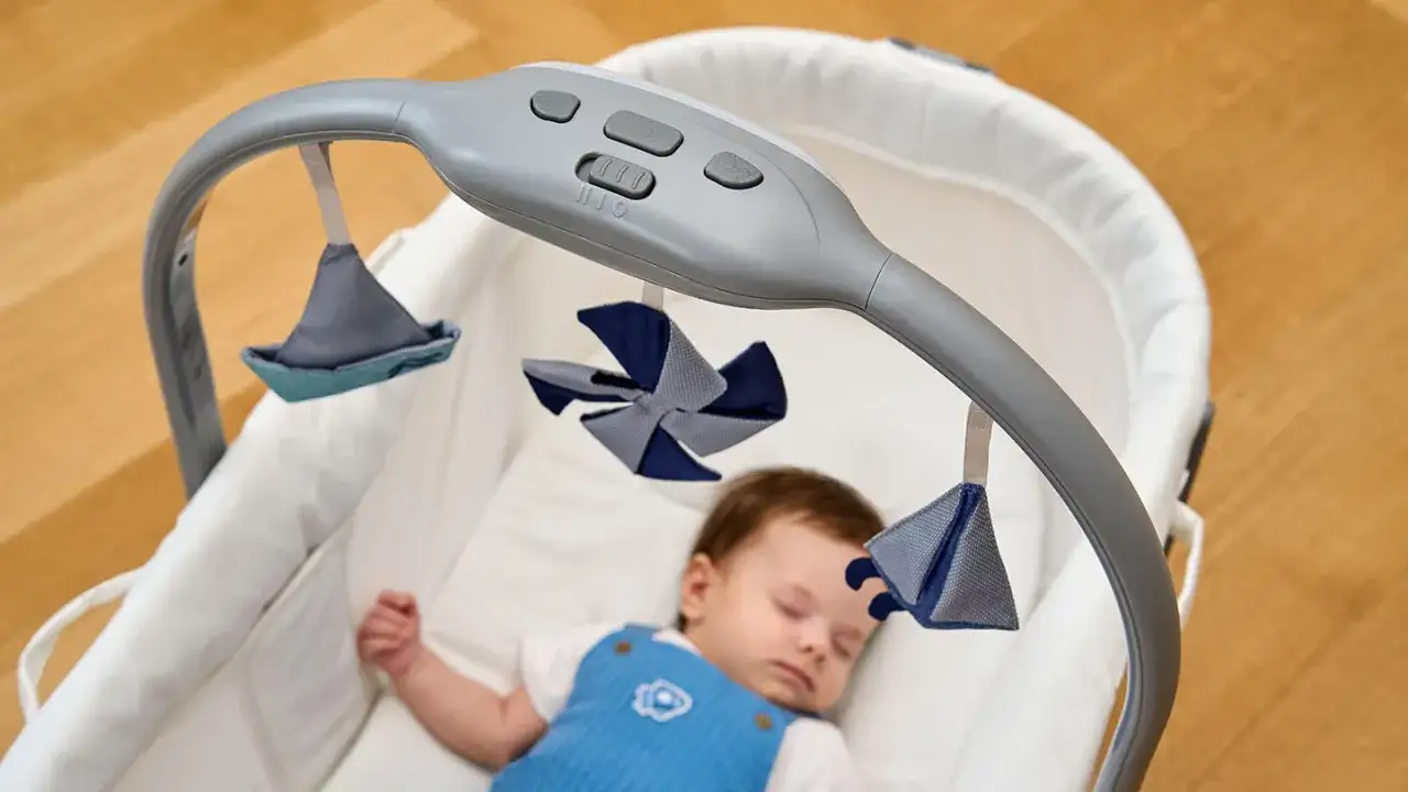 Un neonato dorme sereno nella sua culla, con un giostrina sopra di lui. Un piccolo scatto di crescita di 1 mese, pieno di sogni.