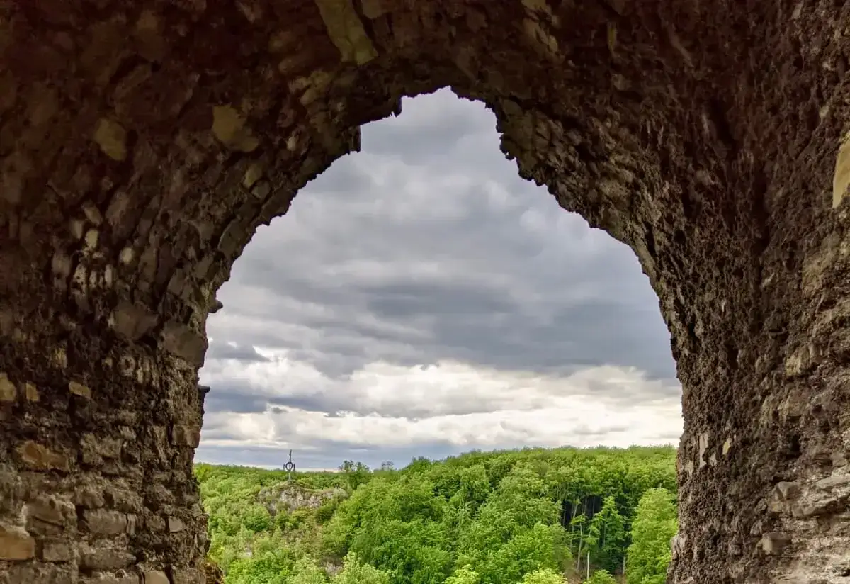 Blick durch einen steinernen Torbogen auf eine bewaldete Landschaft mit einem Denkmal. Ein tolles Motiv für Ausflugsziele Sachsen-Anhalt.