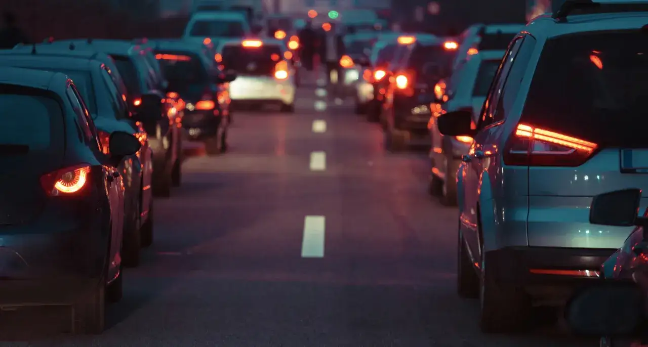 Traffico serale con luci sfocate, come vede le luci un miope. Le auto sono ferme, i fari posteriori rossi e le luci dei lampioni creano aloni.