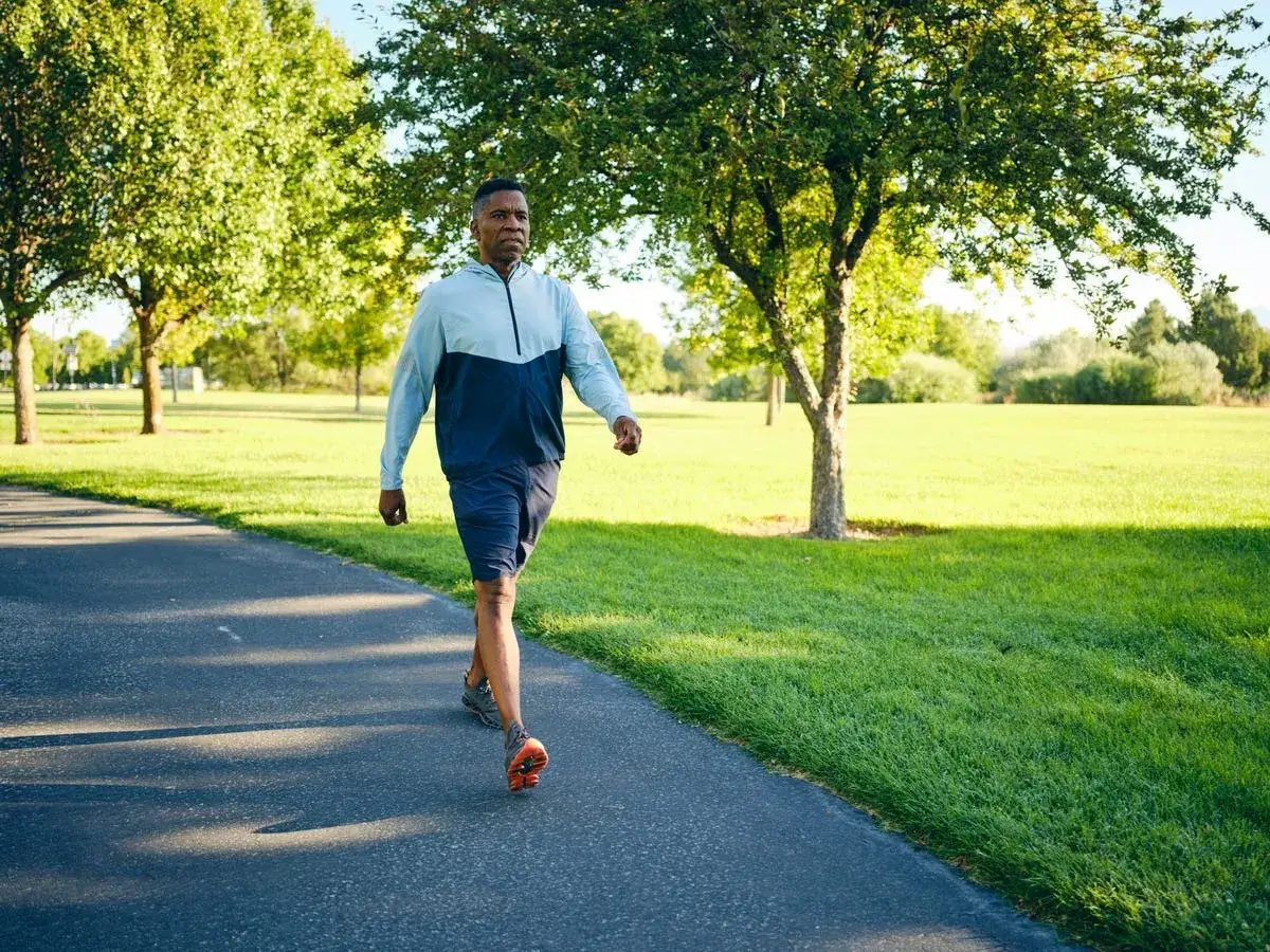 Uomo cammina su un sentiero in un parco, un esempio di come lo **sport contro ansia e depressione** possa migliorare il benessere.