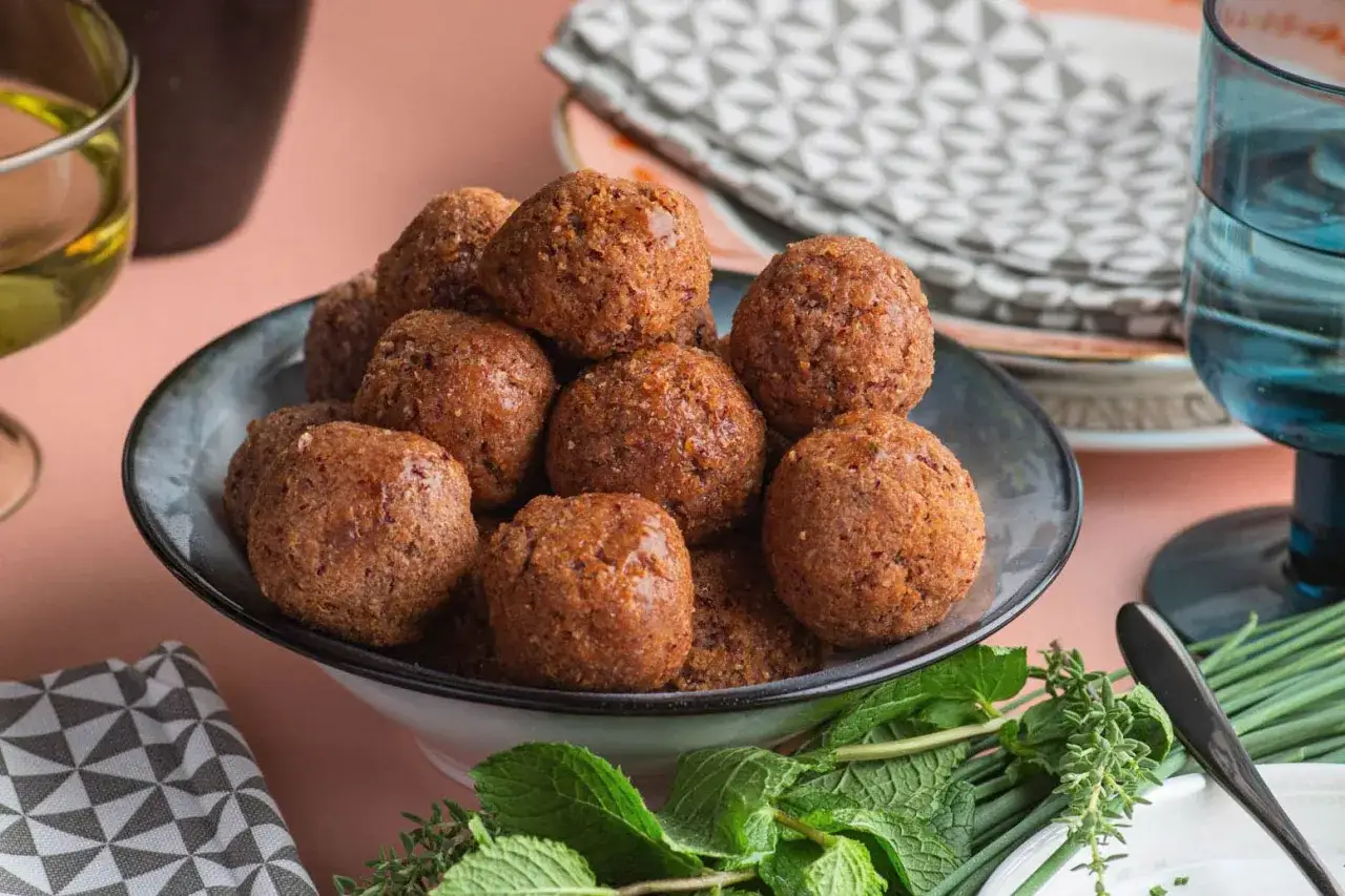 Un piatto colmo di polpette di fagioli dorate, guarnito con erbe fresche.
