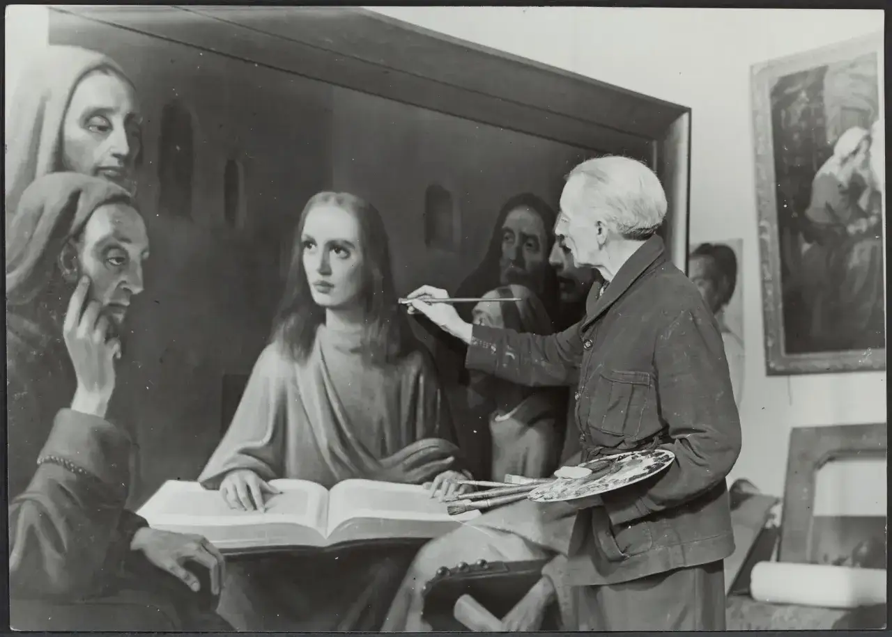 Giuliano Ruffini, artiste peintre, retouche une toile repr&eacute;sentant des figures religieuses. Il tient pinceaux et palette.