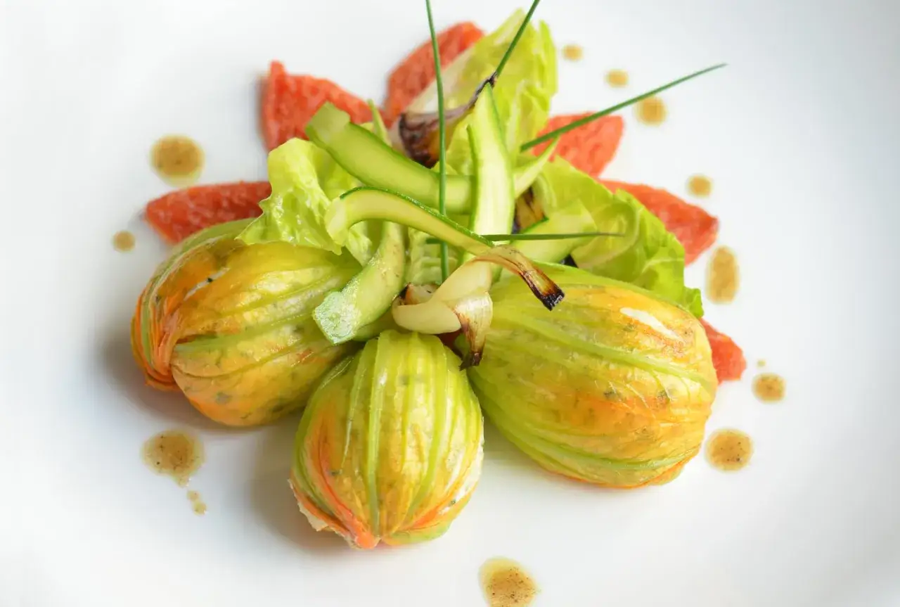 Fleurs de courgettes farcies, garnies de fines lamelles de courgette, de feuilles de laitue et de quelques touches de pamplemousse rose.