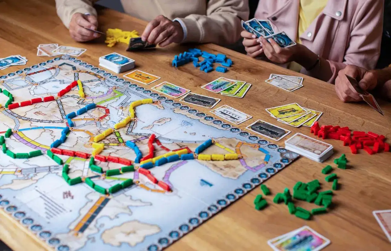 Gracze budują trasy kolejowe na mapie Europy w gry connect. Kolorowe pociągi i karty tworzą strategiczną rozgrywkę.